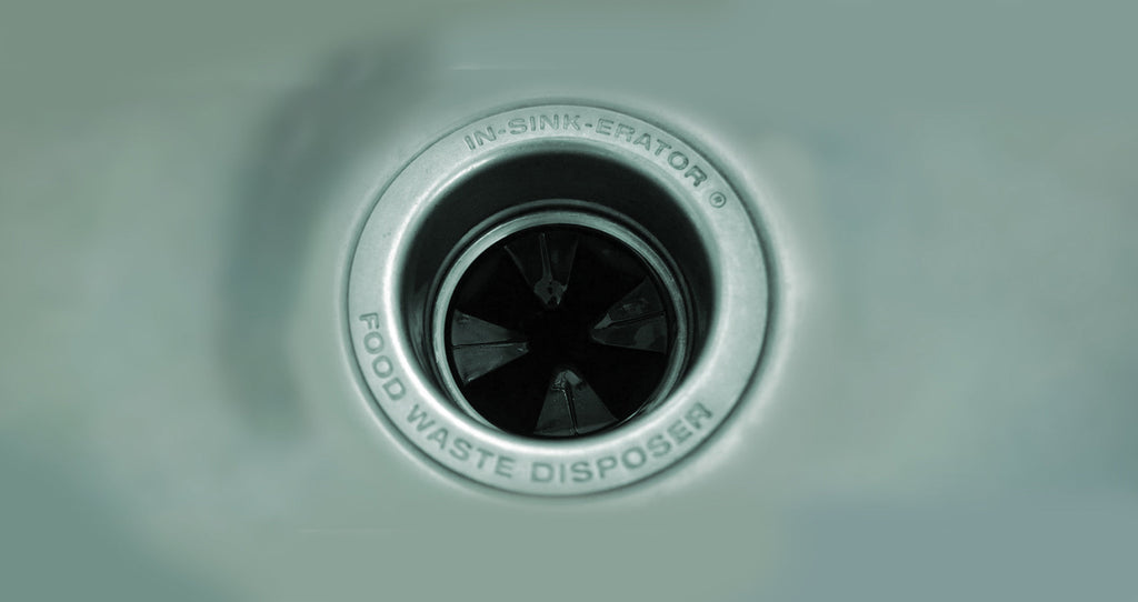 Close view of an In-Sink-Erator food waste disposer opening in a white sink