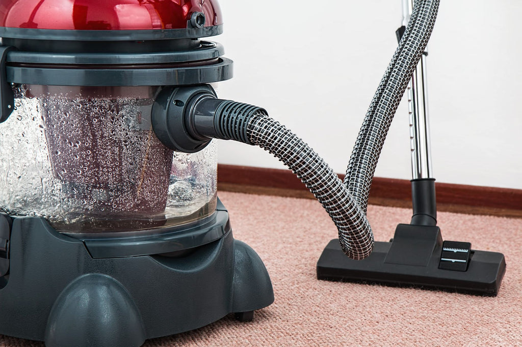 Close-up of a modern vacuum cleaner with water filtration on carpet floor indoors