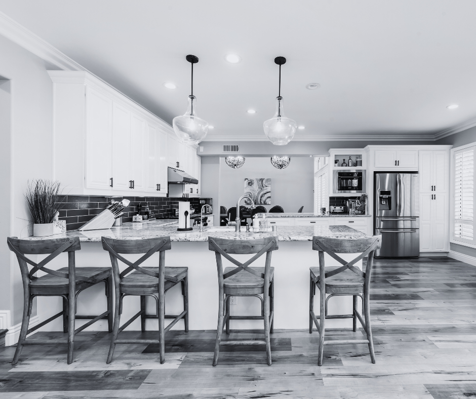 A bright open-plan kitchen with an island, bar stools and a stainless steel refrigerator