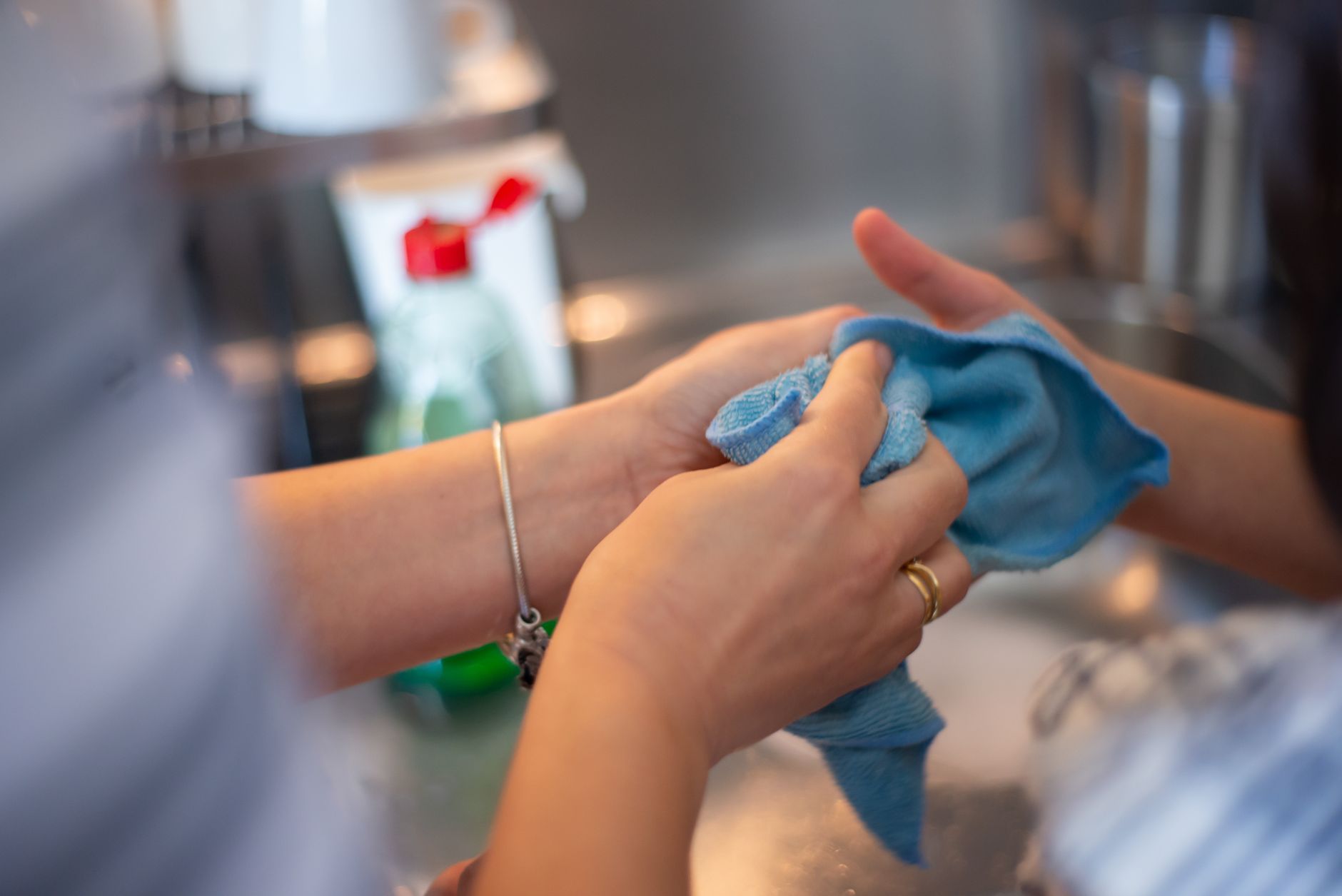 Detailed image of two people cleaning using a blue cloth indoors